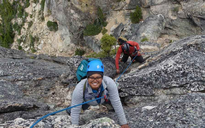 woman smiling while rock climbing on outward bound course for women